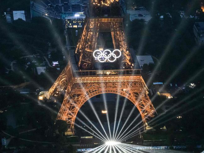 TOPSHOT - A photograph taken from an helicopter on July 26, 2024 shows an aerial view of the Eiffel Tower and the Olympics Rings lightened up during the opening ceremony of the Paris 2024 Olympic Games in Paris. (Photo by Lionel BONAVENTURE / POOL / AFP)