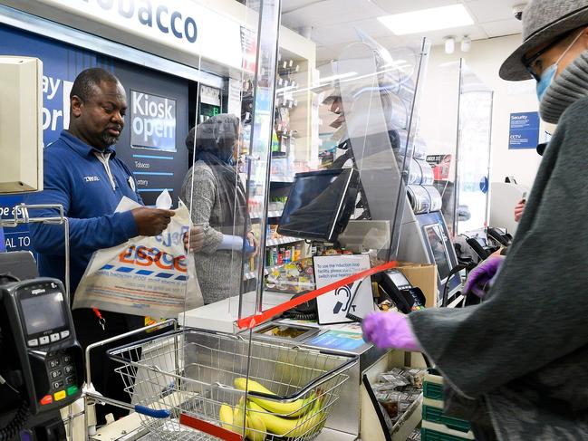 A cashier at a supermarket works behind a protective perspex barrier in London. Picture: AFP