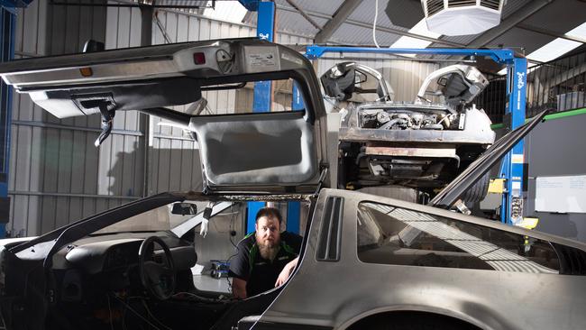 DeLorean Dynamics manager Paul Black with damaged cars and other cars he’s still working on. Picture: Brett Hartwig