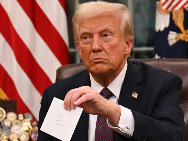 US President Donald Trump holds up outgoing President Joe Biden's letter as he signs executive orders in the Oval Office of the WHite House in Washington, DC, on January 20, 2025. (Photo by Jim WATSON / POOL / AFP) / ALTERNATE CROP