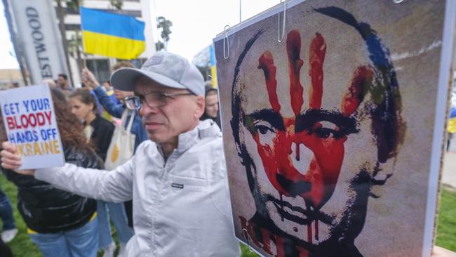 A demonstrator holds a sign showing a picture of Russian President Vladimir Putin with a red hand print during a rally in support of Ukraine in Los Angeles, California. Picture: Ringo Chiu/AFP