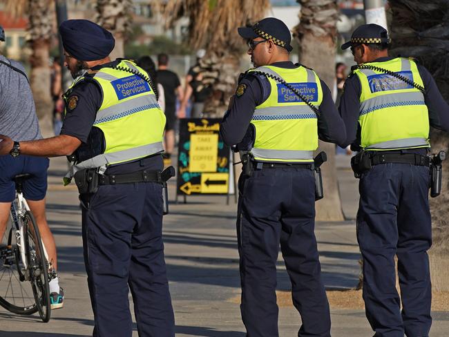 Victoria Police speak to a man at St Kilda beach in Melbourne.