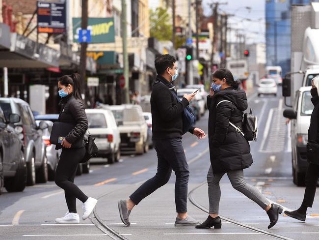 People cross a street in Melbourne on October 11, 2021, during a lockdown against Covid-19 coronavirus as Sydney ended a 106-day lockdown. (Photo by William WEST / AFP)