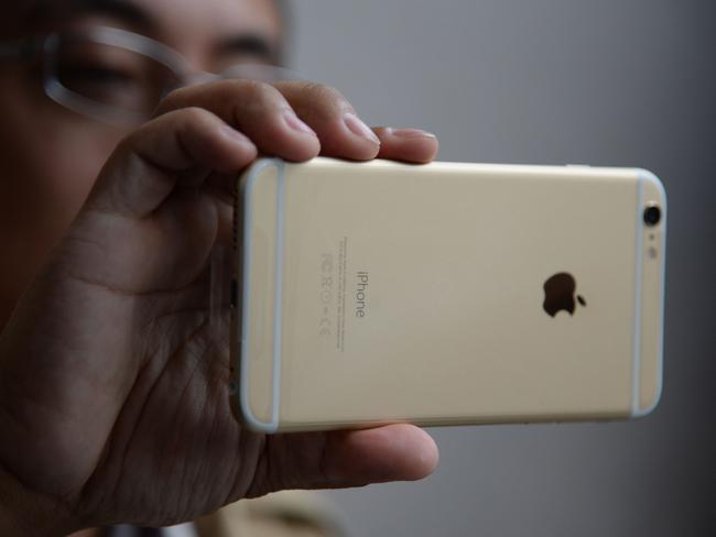 (FILES) This September 19, 2014 file photo shows a man as he checks out his iPhone 6 Plus outside the Apple store in Pasadena, California. A newly discovered family of malware has the capacity to infect iPhones via Apple computers, posing a security threat to devices that have been largely resistant to cybercriminals, researchers said. The researchers at Palo Alto Networks, a cybersecurity firm, said the malware shows 