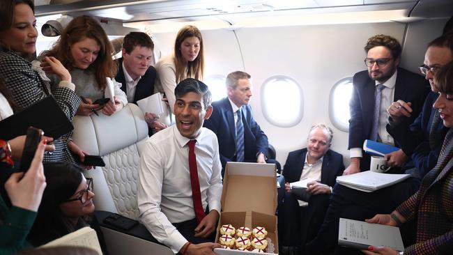 Rishi Sunak presents cupcakes to reporters on the flight to Warsaw. Picture: AFP