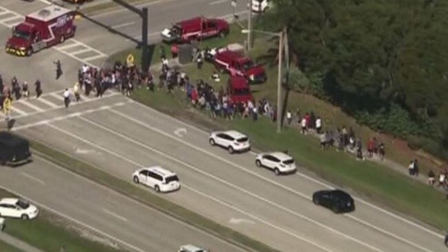 School pupils are led away from the shooting scene at Marjory Stoneman Douglas High School in Parkland. Picture: Fox 13.