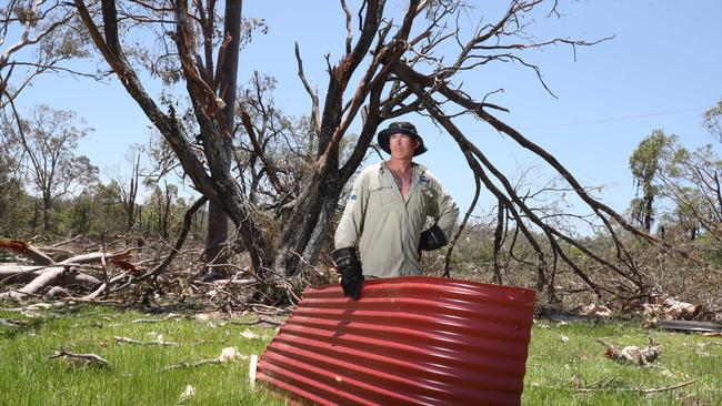 Storm recovery at Oxenford. Adam Bailey pics up parts of his roof blown several hundred metres away from his house on California Drive. Picture Glenn Hampson