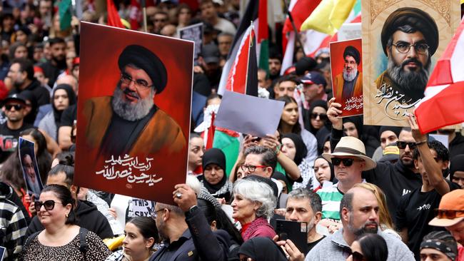 People hold up pictures of Hezbollah leader Hassan Nasrallah at a protest at Town Hall in Sydney on Sunday. Picture: Damian Shaw