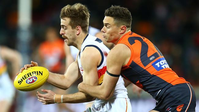 Jordan Gallucci tries to get a kick away under pressure from Giant Josh Kelly. Picture: Mark Nolan/Getty Images