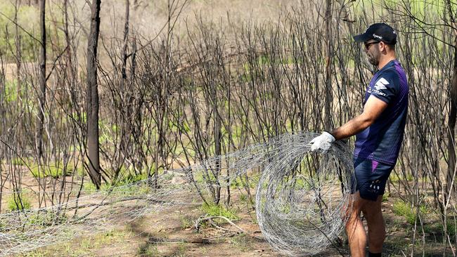 Skipper Cameron Smith carries wire fences destroyed by fire.