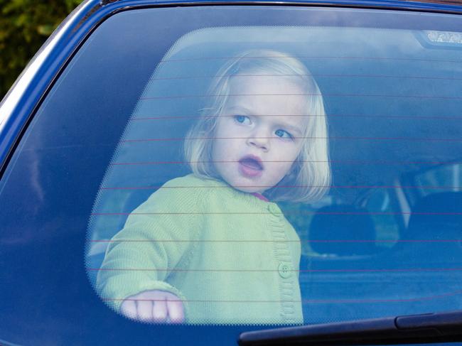 Child girl closed in the back of a car on a hot day. Concept image of danger of overheating in car for young children in the summer - istock