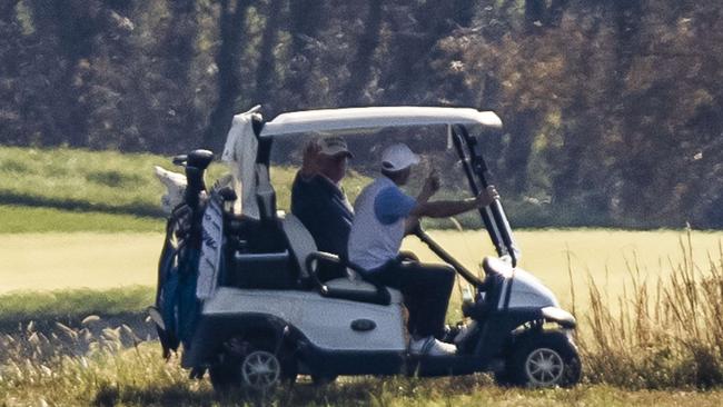 Donald Trump waves to media across the Potomac River as he plays a round of golf at his private club, in Sterling, Virginia. Picture: AFP.