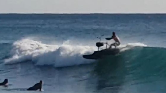 Surfers duck-dive to avoid the careening contraption at Burleigh on the Gold Coast. Picture: Cameron Burke