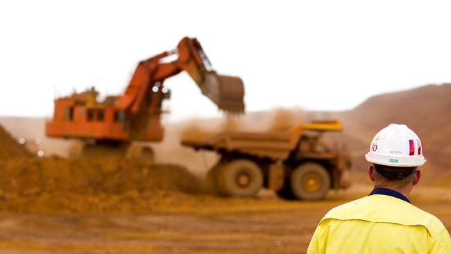 A mine worker watches as a haul truck is loaded by a digger with material from the pit at Rio Tinto Group's West Angelas iron ore mine in the Pilbara. (Photographer: Ian Waldie/Bloomberg)