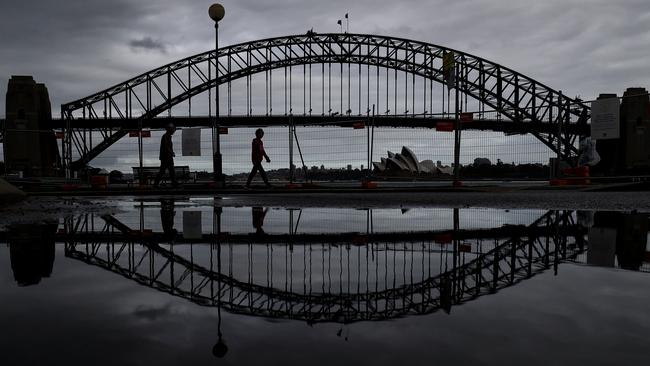 People walk past fencing placed to restrict public access at McMahons Point on Sydney Harbour on Thursday. Picture: Getty Images