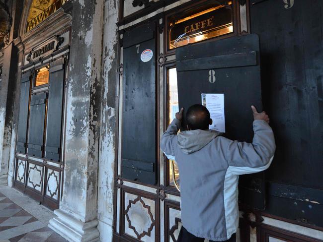 Shutters are placed on the windows of the Cafe Florian in Saint Mark Square just before at 18 o'clock in Venice on March 8, 2020, after millions of people were placed under forced quarantine in northern Italy as the government approved drastic measures in an attempt to halt the spread of the deadly coronavirus that is sweeping the globe. - On top of the forced quarantine of 15 million people in vast areas of northern Italy until April 3, the government has also closed schools, nightclubs and casinos throughout the country, according to the text of the decree published on the government website. With more than 230 fatalities, Italy has recorded the most deaths from the COVID-19 disease of any country outside China, where the outbreak began in December. (Photo by ANDREA PATTARO / AFP)