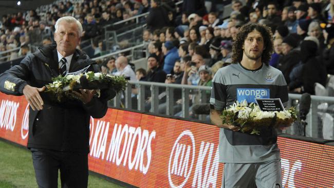 Newcastle manager Alan Pardew, left and captain Fabricio Coloccini carry a wreath of flowers in memory of Newcastle United fans Liam Sweeney and John Alder, who were killed on Malaysia Airlines Flight MH17, before their match with Sydney FC.