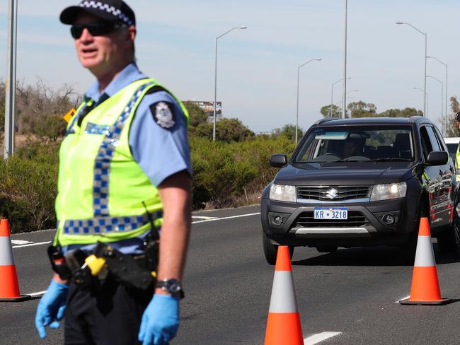 Police officers and Royal Australian Navy personnel are seen stopping drivers at an intrastate checkpoint on the Forrest Highway near the border of the Peel and South West regions, 110km south of Perth on Friday, April 10, 2020. The West Australian Government have enforced strict intrastate border closures prohibiting all non-essential travel with people without an exemption being turned back. (AAP Image/Richard Wainwright) NO ARCHIVING