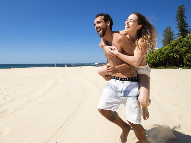 Lucas Faria, 32, and Stephanie Kunde 23, soak up the sunshine welcoming Queenslanders to springtime at Moffat Beach. Picture: Lachie Millard