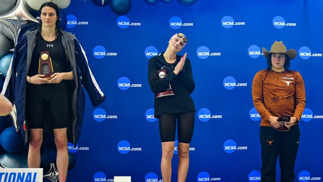 Lia Thomas accepts the winning trophy for the 500 freestyle finals as second placed Emma Weyant and third-place finisher Erica Sullivan look on, during the NCAA Swimming and Diving Championships. Weyant and Sullivan are not among the complainants. Picture: Getty