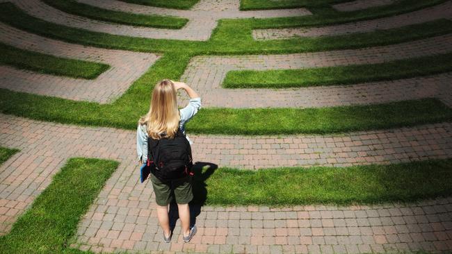 Predictions. A woman teenager student stands looking through the puzzling maze of schooling and the education system, forecasting the way forward and searching for the path to her goal. Concept of student facing uncertainty to their education, life and future career.