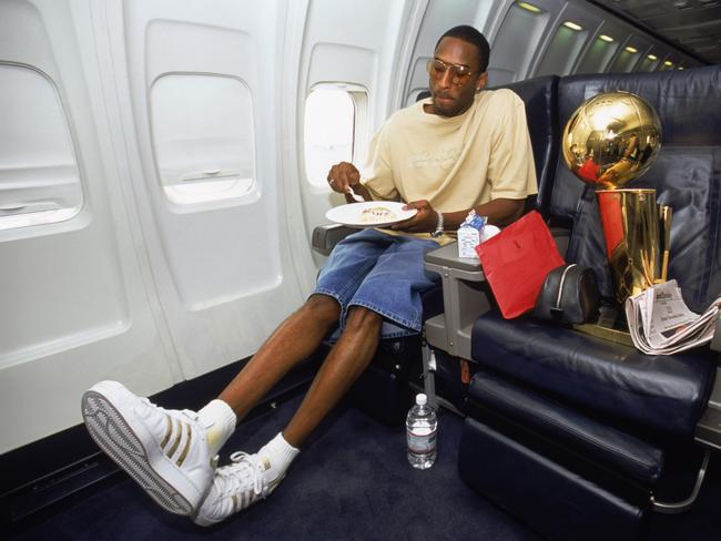 Guard Kobe Bryant #8 of the Los Angeles Lakers eats an in-flight meal with the championship trophy beside him after Game Four of the 2002 NBA Finals against the New Jersey Nets at Continental Airlines Arena in East Rutherford, New Jersey on June 12, 2002. Picture: Getty