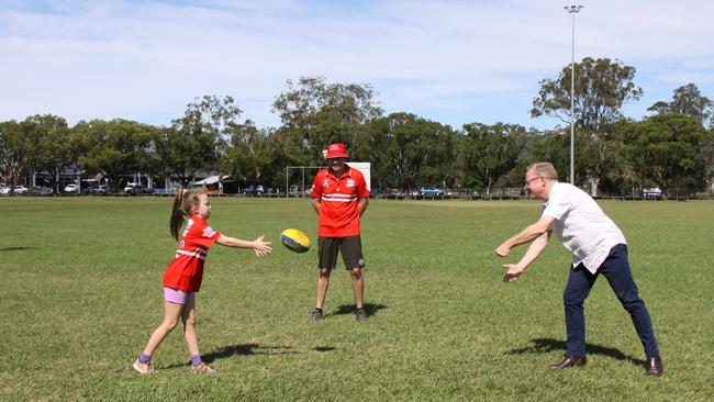 OVAL UPGRADE: Lismore Swans Junior AFL player Katrina McQuilty shows Ben Franklin how to handball as her father Nick looks on. Franklin was there to announce a $115,000 fencing upgrade for Mortimer Oval.