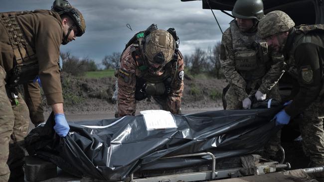 Ukrainian servicemen and paramedics load a bag containing the body of a fallen Ukrainian serviceman in to a medical evacuation vehicle on a road near Bakhmut. Picture: AFP.