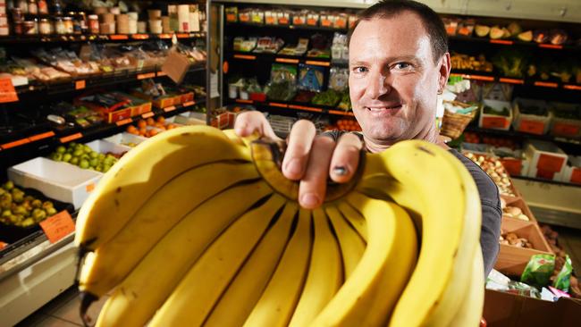 Peter Fuller unpacks bananas at Greenies Real Food in Rapid Creek. Despite the impending doom facing Territory grown bananas the popular fruit will remain available to purchase across the state.