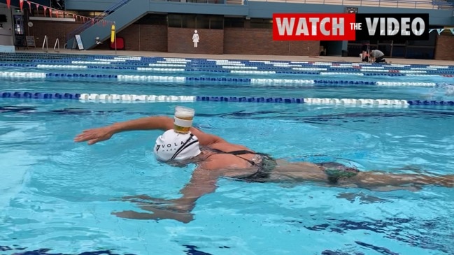 Susie O'Neill swims a lap of the pool balancing a beer on her head