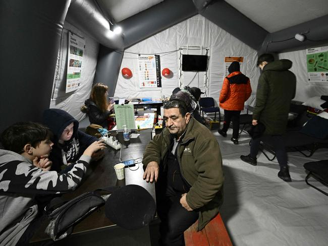 People charge their devices, use internet connection and warm up inside a mobile heating point set in the town of Vyshgorod, outside of Kyiv. Picture: AFP