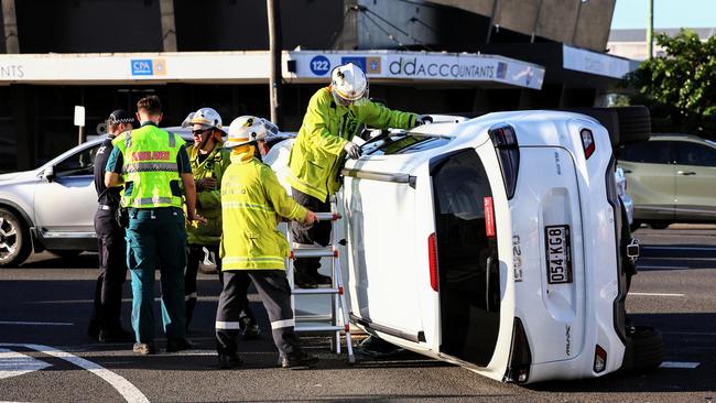 Queensland Fire and Emergency Services firefighters attend to the scene of a traffic collision between two utilities at the intersection of Sheridan and Minnie Streets, where one ute rolled onto its side. Picture: Brendan Radke