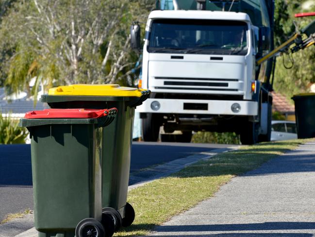 Focus on two Rubbish bins with rubbish truck in background lifting a bin