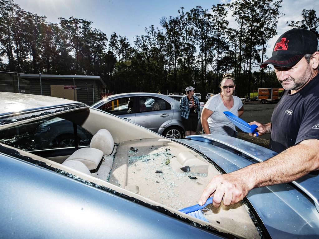 Sherry and Rick Duckworth from Gympie clean the glass out of their car after their back windscreen was shattered during a wild hailstorm at Glenview. 'One minute we were queuing up for fuel eating ice blocks the next we were being absolutely peppered with ice blocks'. Photo Lachie Millard