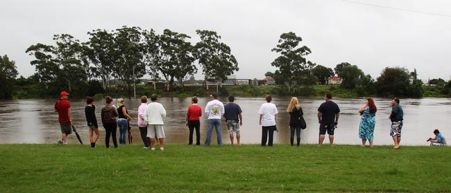 People line the bank of the Hawkesbury River, swollen by the overflowing Warragamba Dam.