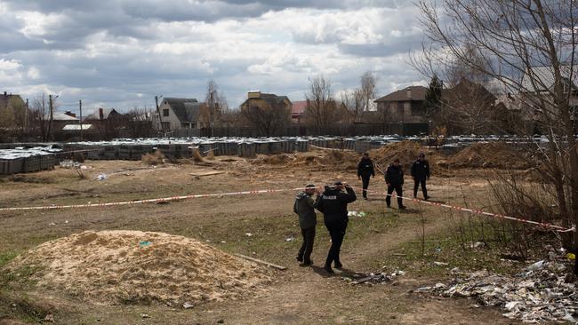 Police officers walk into the mass grave site in Bucha, Ukraine. Picture: Getty Images.