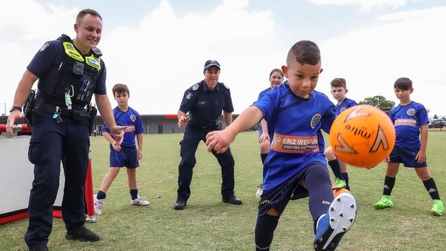 Constable Tyler Sherlock and Sen-Sgt Trev Blair with James and his Craigieburn City Football Club teammates. Picture: Ian Currie