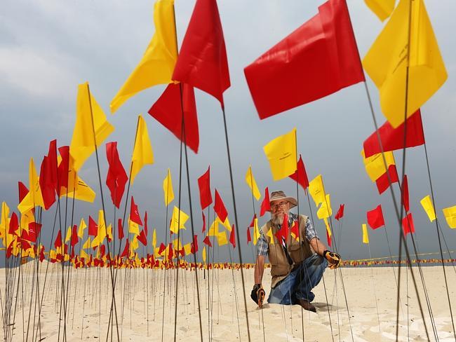 Artist Carl Billingsley putting the finishing touches on his Red Centre on Tamarama Beach.