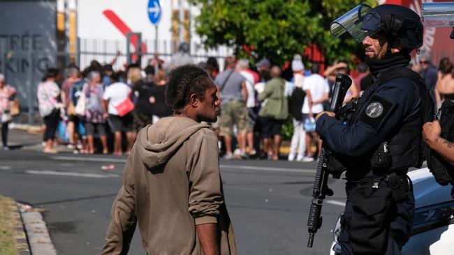 A police officer interacts with a man as others queue to enter a supermarket in the Magenta district of Noumea at the weekend. Picture: Theo Rouby/AFP