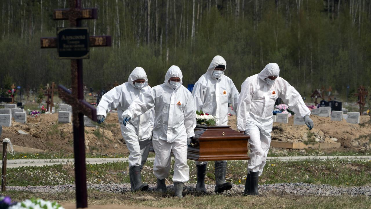 Gravediggers wearing protective suits carry the coffin of a COVID-19 victim as relatives and friends stand at a safe distance in St Petersburg, Russia. Picture: Dmitri Lovetsky/AP