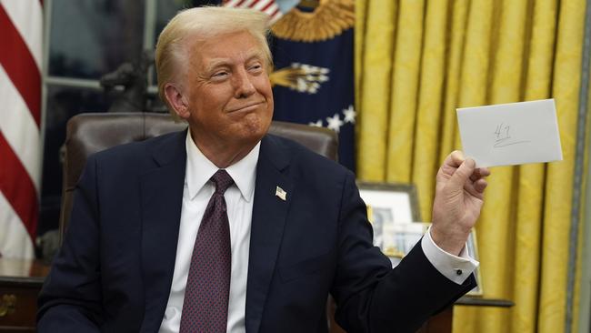 President Donald Trump holds up the letter that former president Joe Biden left for him in the desk as he signs executive orders in the Oval Office. Picture: AP