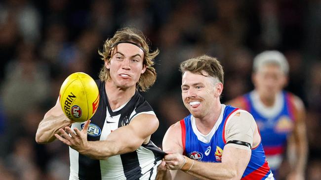 MELBOURNE, AUSTRALIA – MAY 31: Harvey Harrison of the Magpies handpasses the ball as he's tackled by Lachlan Bramble of the Bulldogs during the 2024 AFL Round 12 match between the Collingwood Magpies and the Adelaide Crows at The Melbourne Cricket Ground on May 31, 2024 in Melbourne, Australia. (Photo by Dylan Burns/AFL Photos via Getty Images)