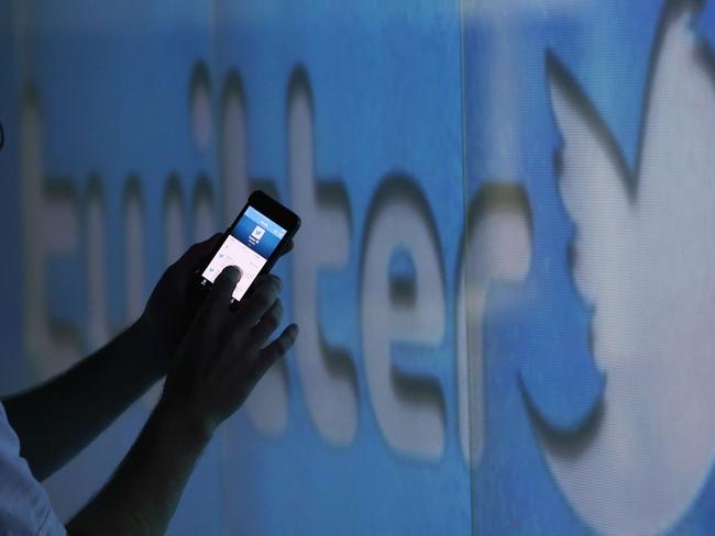 A user scrolls through a Twitter feed on the screen of an Apple Inc. iPhone 5 smartphone in this arranged photograph taken in London, U.K., on Friday, Oct. 4, 2013. Twitter Inc.'s initial public offering documents suggested a valuation of $12.8 billion for the microblogging service, underscoring the seven-year rise of a still unprofitable company that has helped revolutionize how people share information. Photographer: Chris Ratcliffe/Bloomberg