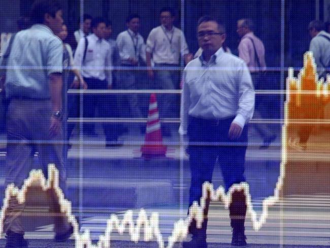 Pedestrians are reflected on a share prices board in Tokyo on June 22, 2015. Japan's share prices rose 161.07 points to close at 20,335.31 points at the morning session of the Tokyo Stock Exchange, as Greece presented its creditors with new proposals to reform its bailout, fuelling hopes it will avert a default and a possible exit from the eurozone. AFP PHOTO / Yoshikazu TSUNO