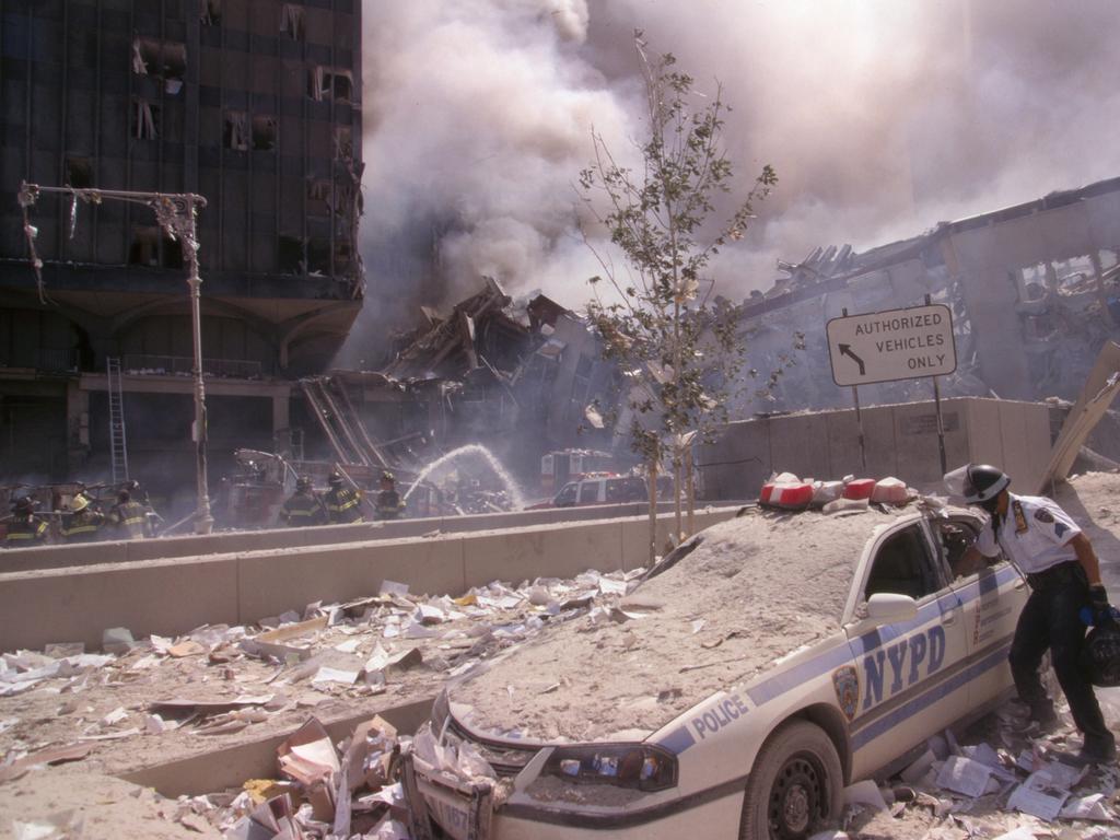 A police officer reaches into a debris and ash-covered police car in lower Manhattan. Picture: Alamy