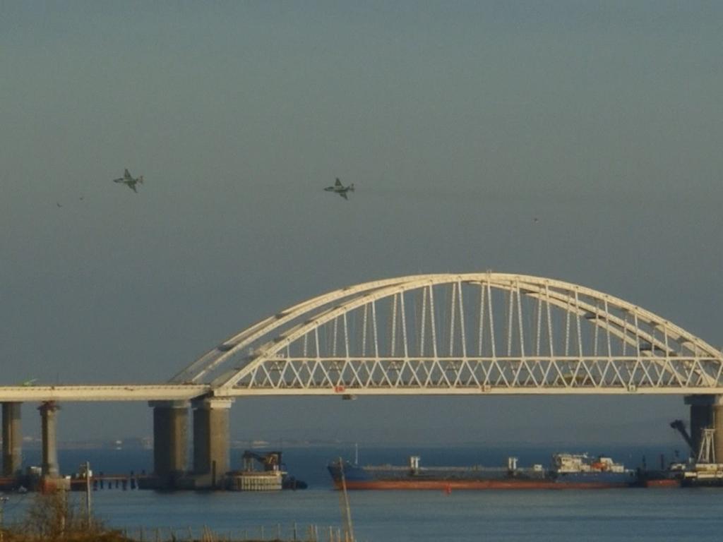 This video grab shows Russian strike aircraft flying over the Crimean Bridge that spans the Kerch Strait, a narrow strip that links the Azov and Black seas, as a Russian ship blocks the entrance. Picture: AFP