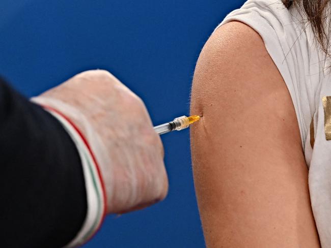 A medical worker (L) injects a woman with a dose of the British-Swedish AstraZeneca/Oxford vaccine on March 24, 2021 at a vaccination hub outside Rome's Termini railway station, as the vaccination campaing continues despite delays across the country . (Photo by ANDREAS SOLARO / AFP)