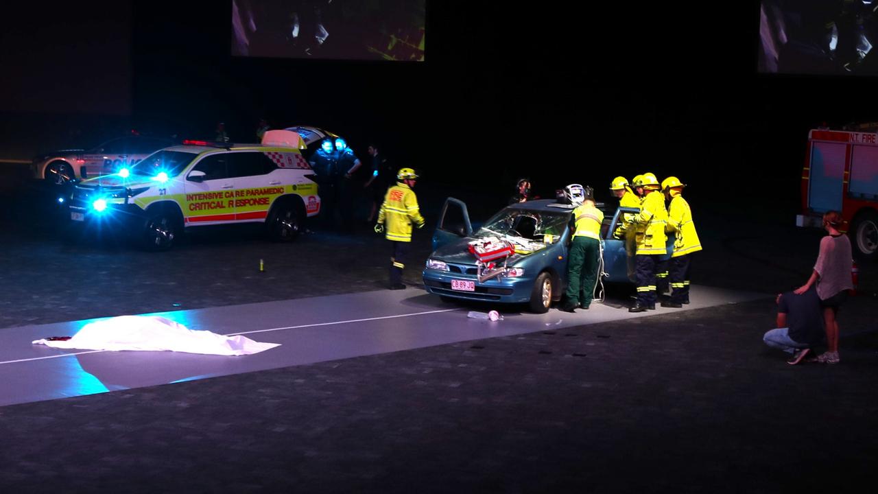 Ambulance and firefighters work to extract a screaming, injured “passenger” while another passenger lies dead on the road, having flown through the windshield. Picture: George Yankovich