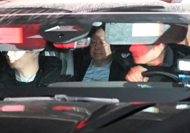 Impeached South Korean President Yoon Suk Yeol (C) is seen inside a vehicle as he leaves the complex housing investigators