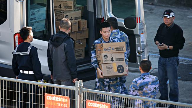 Chinese personnel load boxes of baby milk on to a warship last week. Picture: Adam Yip